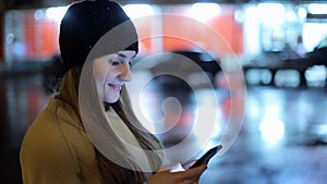 Girl pointing finger on screen smartphone on background illumination bokeh color light in night atmospheric city