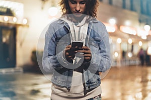 Girl pointing finger on screen smartphone on background illumination bokeh light in night atmospheric city