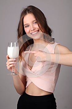 Girl points her finger at the bocal of milk. Close up. Gray background photo