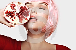 Girl with pomegranate. Pink hair. Makeup