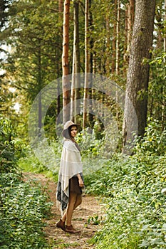 A girl in a poncho and a hat in forest
