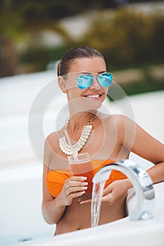 Girl in pool with a glass of red cocktail