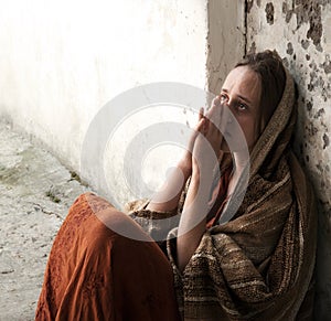 A girl in poor clothes sits on the ground