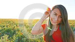 Girl on the poppy fields. Red flowers with green stems, huge fields. Bright sun rays.