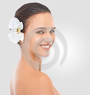 Girl, portrait and flower with glow for skincare in studio, beauty and natural makeup for blossom. Woman, orchid and