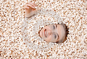 Girl portrait in popcorn. Image of beautiful european woman 20s eating popcorn. Eating popcorn. Young woman buried in