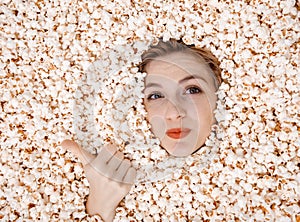 Girl portrait in popcorn. Image of beautiful european woman 20s eating popcorn. Eating popcorn. Young woman buried in
