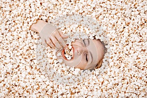 Girl portrait in popcorn. Image of beautiful european woman 20s eating popcorn. Eating popcorn. Young woman buried in