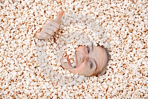 Girl portrait in popcorn. Image of beautiful european woman 20s eating popcorn. Eating popcorn. Young woman buried in