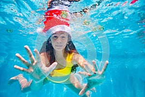 Girl portrait underwater in pool wearing Santa hat