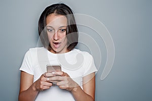 Girl portrait using mobile phone on gray background