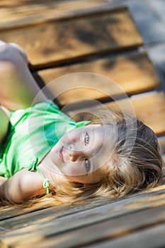 Girl posing at camera lying on the bench, shot from above