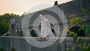 Girl posing castle balcony calm summer evening. Woman leaning on stone railings