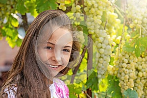 Girl is posing in front of ripe grapes. in sunlight
