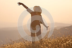 Girl posing on mountain and having fun on idyllic field at sunset