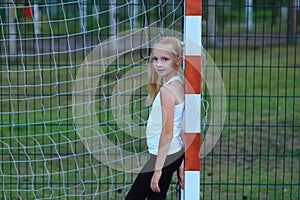A girl posing near a football goal on a sports field.