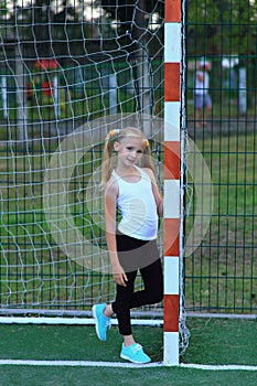 A girl posing near a football goal on a sports field.