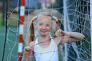 A girl posing near a football goal on a sports field.