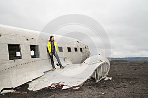 Girl posing near remainings of crashed airplane