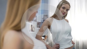 Girl posing in new white shirt near mirror, adolescent development, future model