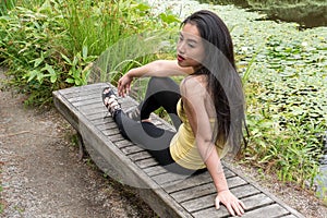 Girl posing on park bench leans backwards