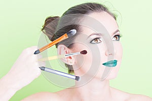 Girl posing with professional trendy make-up holding brushes