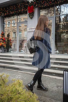 Girl posing on road on winter background. Glamorous funny young woman with smile wearing stylish blue long fur coat