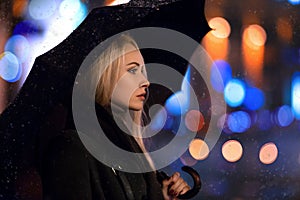 Girl posing with umbrella in the light of evening city