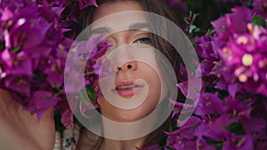 Girl posing violet flowers bush background portrait. Woman touching blossom