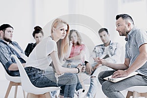 Girl with post traumatic stress during psychotherapy group session with counselor photo