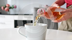 Girl Pouring Apple Juice Into Glass In The Kitchen, In Slow Motion