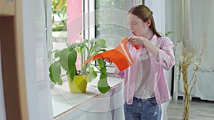 Girl pouring plant with water can.