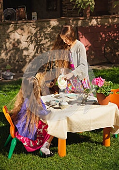 Girl pouring tea to her sister at toy tea party