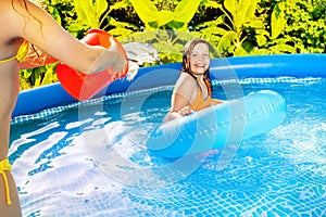 Girl pouring water from red bucket over her friend