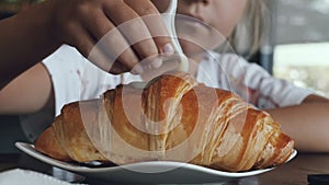 Girl pours condensed milk on a croissant