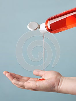 The girl pours liquid soap or red shower gel into an open palm