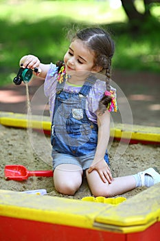 Girl pours out sand in the sandbox on the