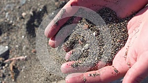 Girl pours sand from her hands on the beach.Slow motion.