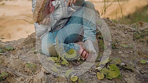 A girl pours sand from her sneakers while sitting on the ground