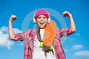 Girl power. Happy skater flex arms on blue sky. Little child with penny board outdoors. Power slide trick. Friction