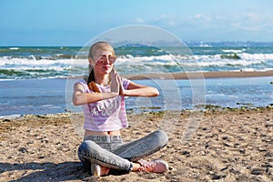 The girl practices yoga by the sea. Exercise gymnastics in the fresh air by the sea.