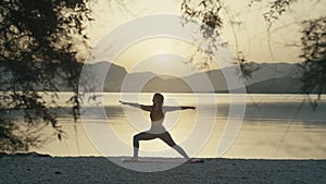 Girl practices yoga at sunset by the ocean.