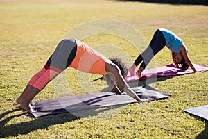 Girl practicing downward facing dog positiong with trainer