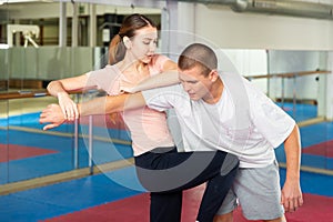 Girl practicing knee kick with arm hold to man in self defence training