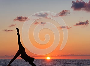 Girl practicing yoga against the background of the ocean and sun