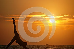 Girl practicing yoga against the background of the ocean and sun