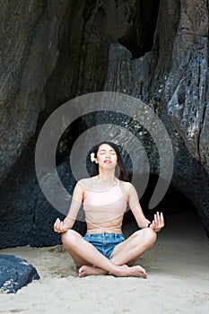 Girl practicing yoga in the shade of a beach cave