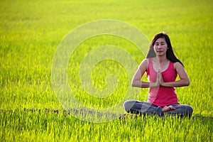 Girl practicing yoga,sitting in paddy field