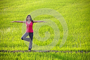 Girl practicing yoga,standing in paddy field