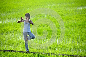 Girl practicing yoga,standing in paddy field